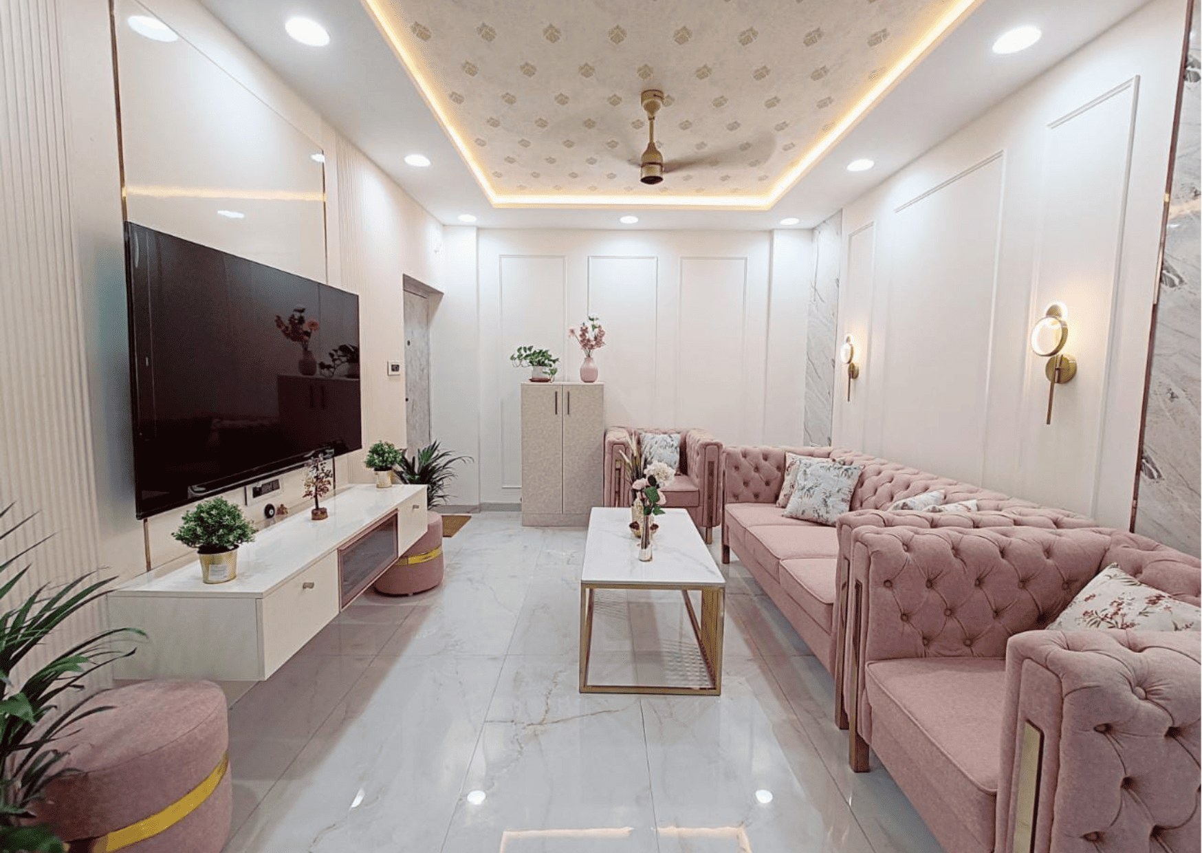 A living room decorated in a pink theme featuring a sofa, a centre table, and a TV console.